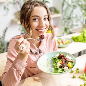 Woman smiling while eating healthy meal at home