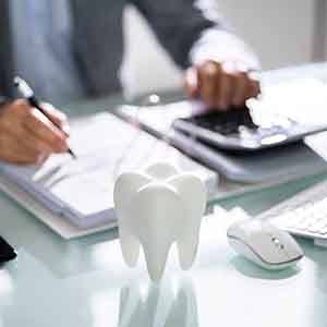 A tooth in front of a businessperson calculating a bill