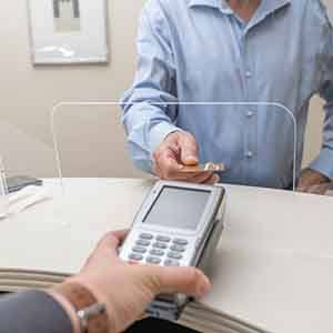 A man paying the cost of dental implants