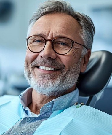 Older man smiling in the dentist’s chair and using dental insurance in Roswell