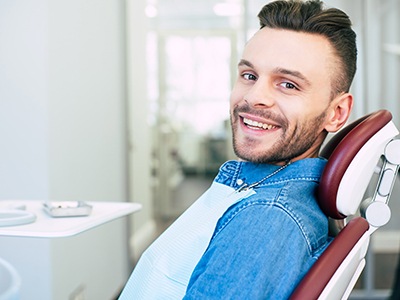 Man in denim jacket smiling in dental chair