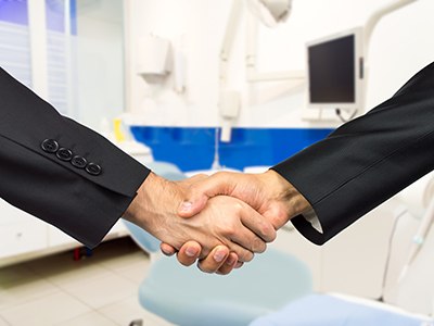 Close-up of handshake in front of a dental chair