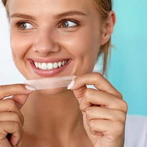 patient smiling while holding whitening strip